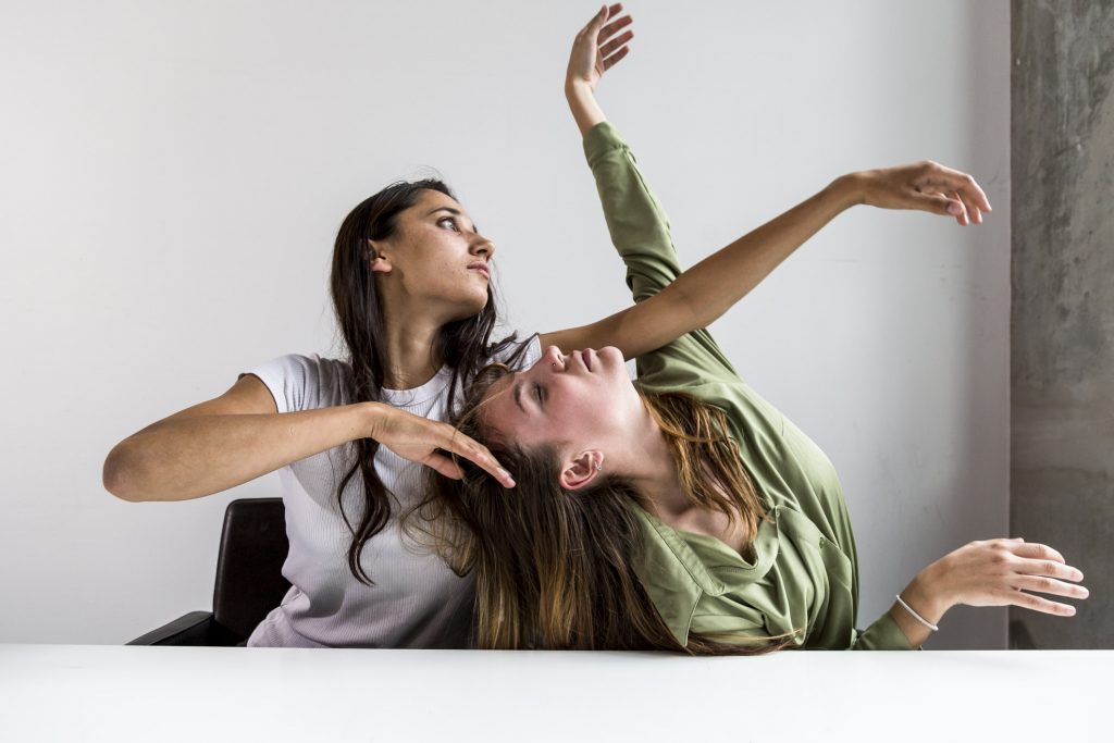 Two young women in abstract pose with arms raised